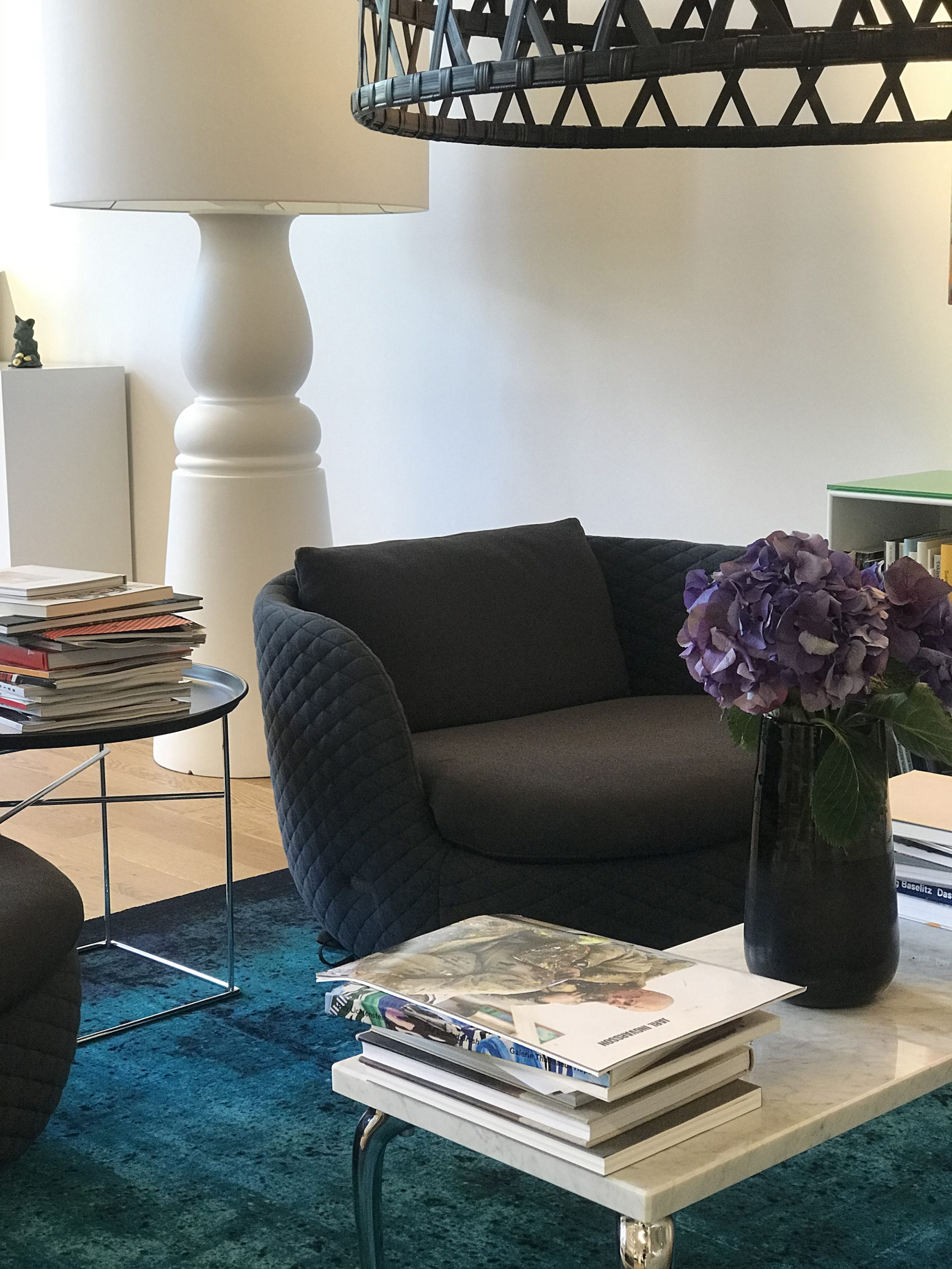 Svart fåtölj framför marmorbord på blå matta