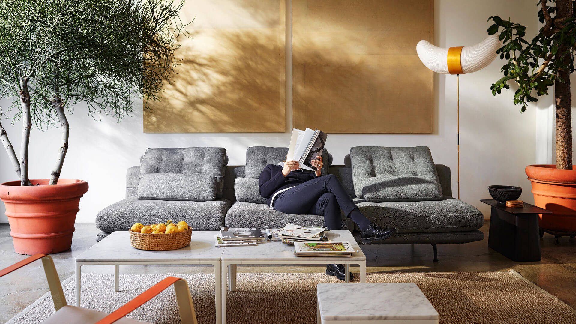 Person sitter i grå soffa och läser magasin