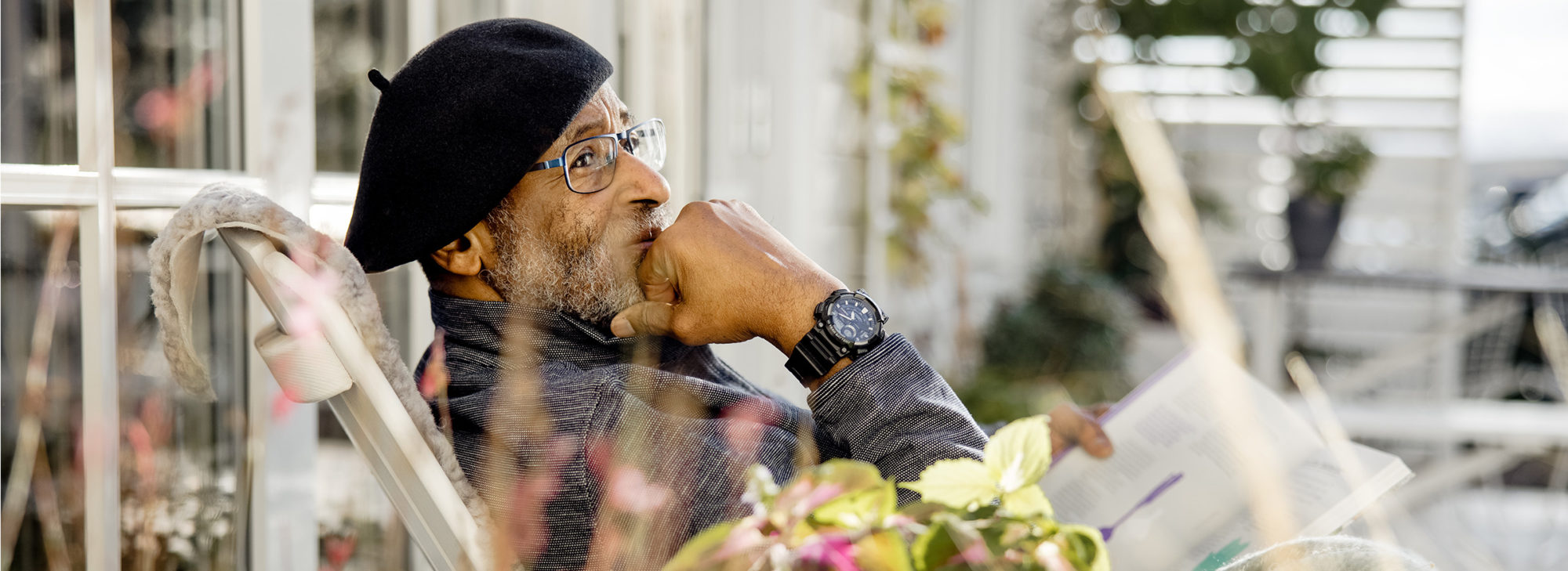 Äldre man med basker som ser fundersam ut och läser en bok