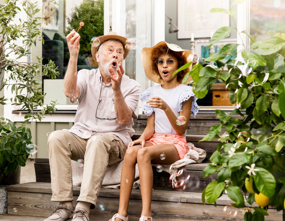Äldre man och barn blåser såpbubblor Phoniro välfärdsteknik
