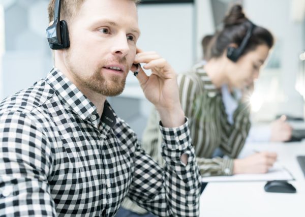 Ung man med headset som sitter vid dator som jobbar på supportavdelning