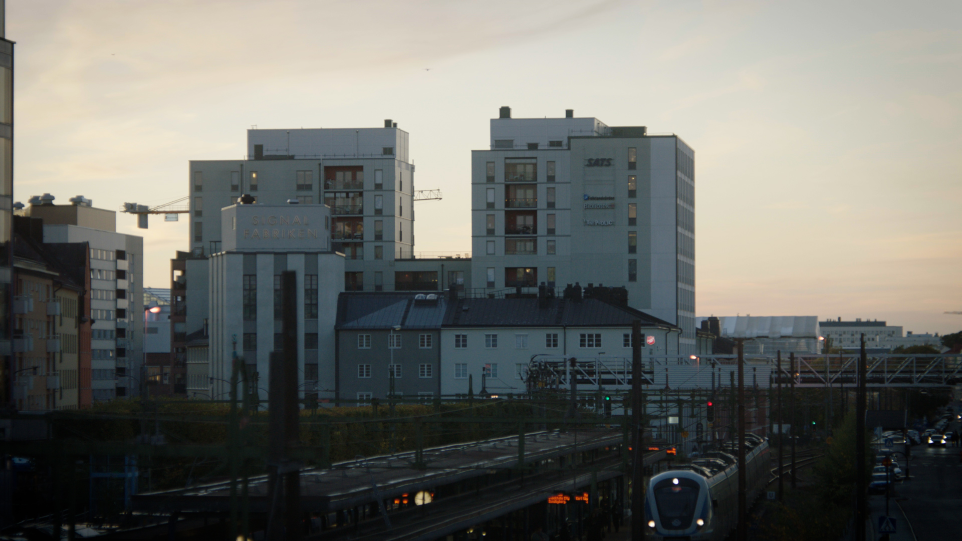 Tågstation och lägenhetshus i kvällsljus.