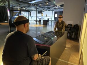 Personer sitter vid en utställning som är ett spel där man använder hjärnan för att styra