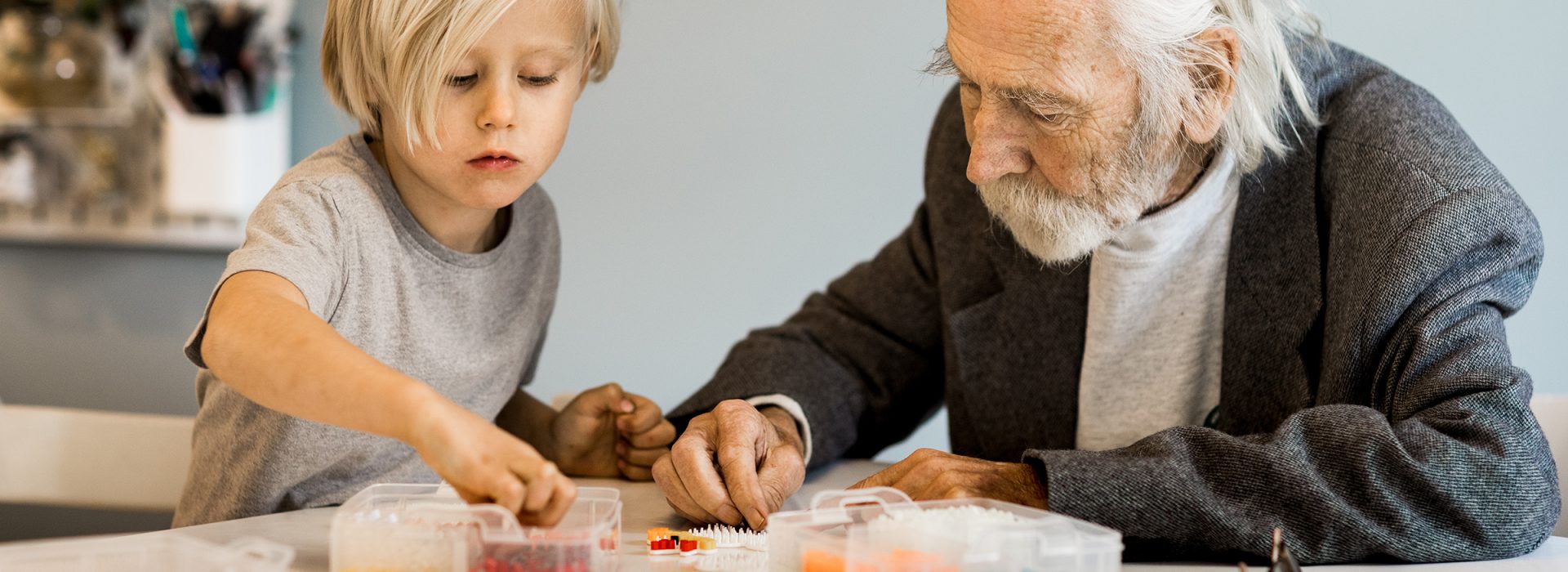 Äldre man som pysslar med pärlor med liten pojke