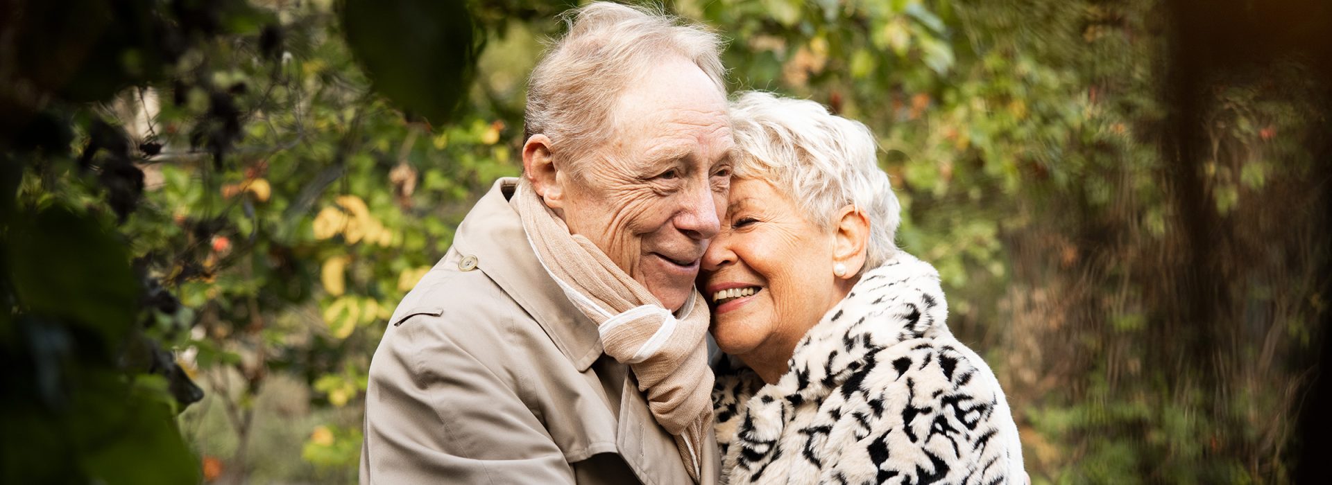 Äldre par som kramas i grön miljö